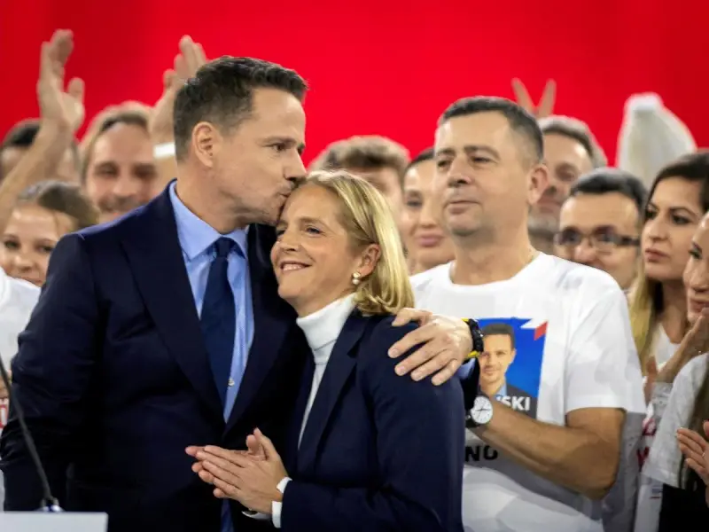Rafał Trzaskowski, choć nie znamy jego dokładnego wieku, czule całuje żonę na tle tłumu.