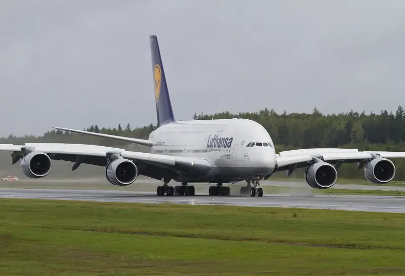 Lufthansa A380, największy samolot pasażerski, kołuje po mokrym pasie startowym.