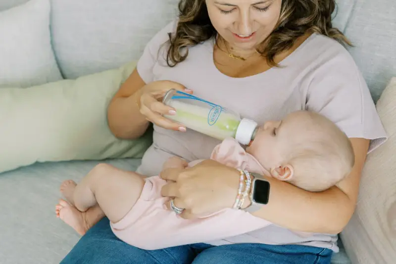 Kiedy zmienic przeplyw smoczka? Mama karmi dziecko butelką, obserwując, czy maluch nie ma problemów z jedzeniem.