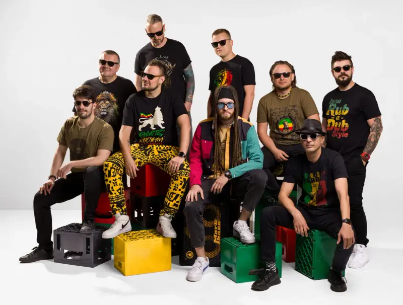 Grupa mężczyzn w koszulkach z motywami nawiązującymi do rastafarianizmu. Jeden z nich ma dredy i kolorową kurtkę, co może kojarzyć się z tym, czym jest rastafarianizm.