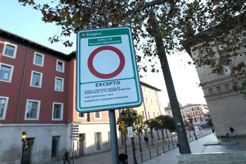 Señal de etiqueta medioambiental en Zaragoza, indicando zona de bajas emisiones con excepciones para carga, descarga, taxis, bicicletas y residentes.