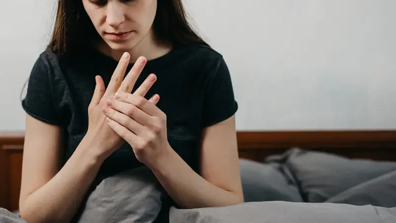 Kobieta masuje dłoń, odczuwając drętwienie rąk w nocy.