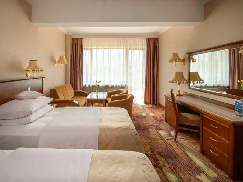 Pokój w hotelu Gołębiowski Wisła: dwa łóżka, kanapa, fotele, biurko i lustro.
