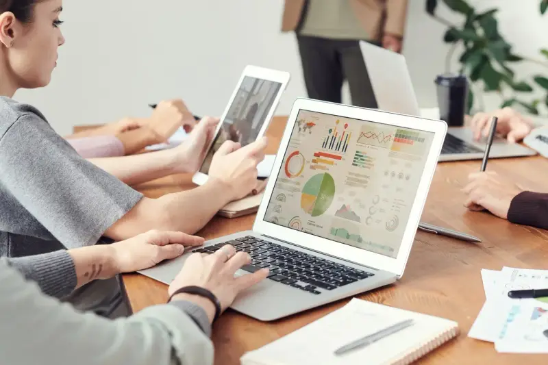 Analityk finansowy pracuje nad raportem na laptopie, analizując wykresy i dane.