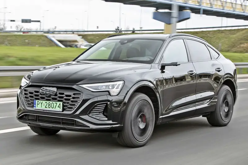 Czarny Audi Q8 e-tron sunie po drodze. Zastanawiasz się nad audi q8 cena? Ten luksusowy SUV coupe robi wrażenie.