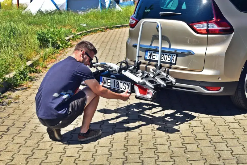 Mężczyzna montuje tablicę rejestracyjną na bagażniku rowerowym, by uniknąć mandatu za brak tablicy rejestracyjnej na bagażniku rowerowym.