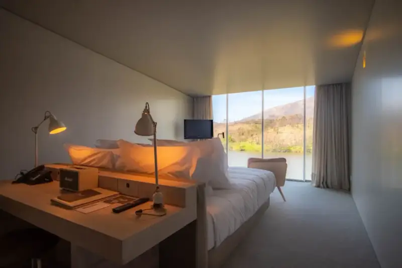 Un angolo studio in camera da letto con vista sul lago. Due lampade illuminano la scrivania con telefono e altoparlante.