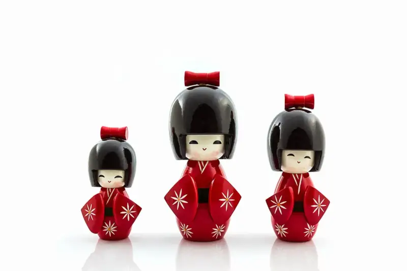 Trzy urocze lalki kokeshi w czerwonych kimonach z białymi wzorami. Idealny pomysł, co przywieźć z Japonii jako pamiątkę.