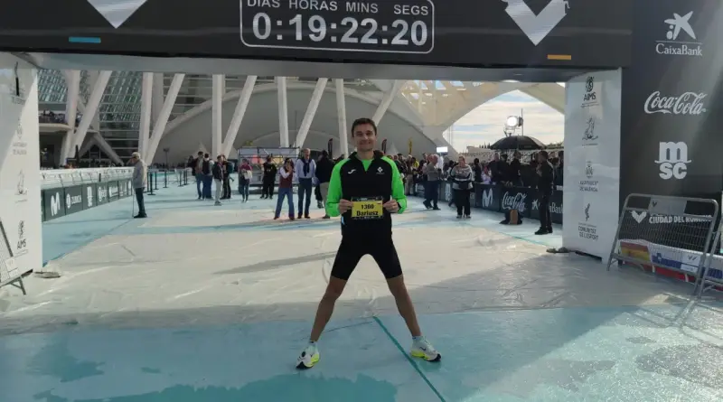 Uśmiechnięty Dariusz z numerem 1360 na piersiach po biegu na maratonie Valencia. Czas na tablicy: 0:19:22:20.