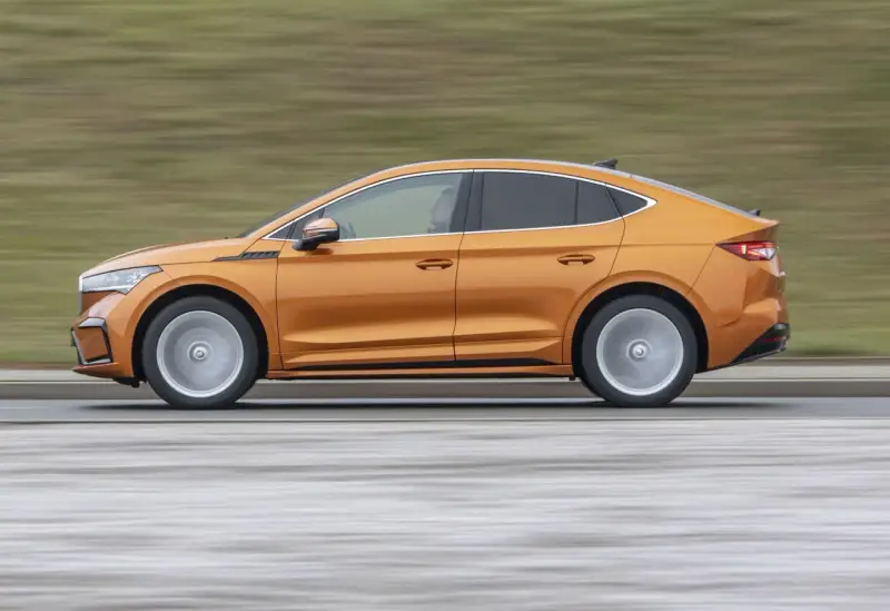 Pomarańczowy elektryczny SUV coupe w ruchu, widok z boku.