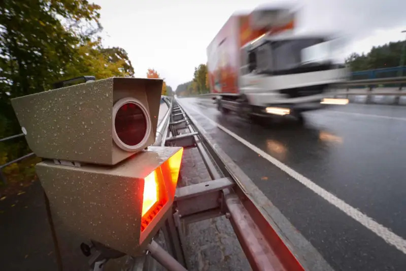 Blitzlicht erhellt die nasse Fahrbahn. Ein LKW rast vorbei. Das Zeugnisverweigerungsrecht bei Blitzern ist ein Thema für Fahrer.