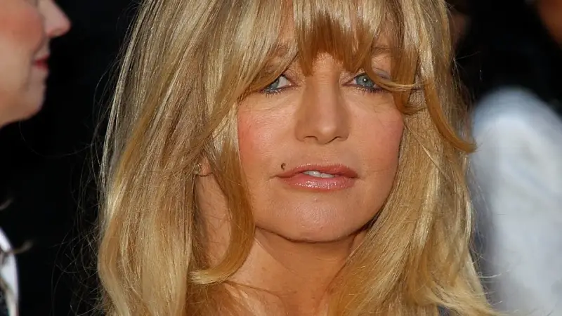 Goldie Hawn ler mot kameran, hennes blonda hår faller runt ansiktet. Tänker på alla roliga filmer med Goldie Hawn.