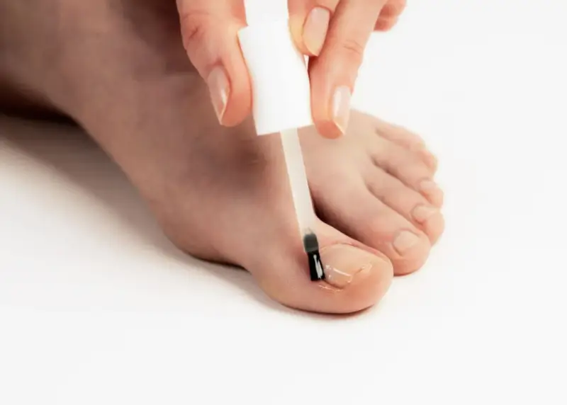Application d'un soin transparent sur un ongle abîmé pour le protéger et le renforcer.