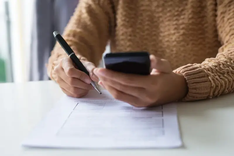 Kobieta z telefonem w dłoni wypełnia formularz, dokonując zgłoszenia darowizny online.
