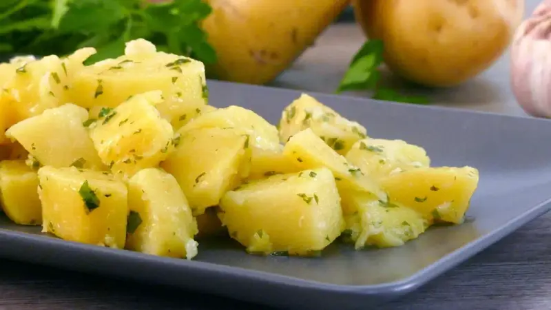 Patatas al microondas cortadas en cubos, aliñadas con perejil y ajo. Un plato sencillo y delicioso.