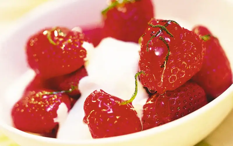 En skål med saftiga, limemarinerade jordgubbar och vispad grädde. En härlig sommardessert.