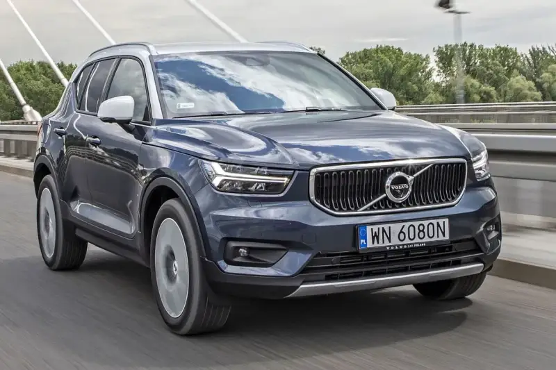 Ciemnogranatowy Volvo XC40 jedzie po moście. Sprawdź aktualną volvo xc40 cena i ofertę.