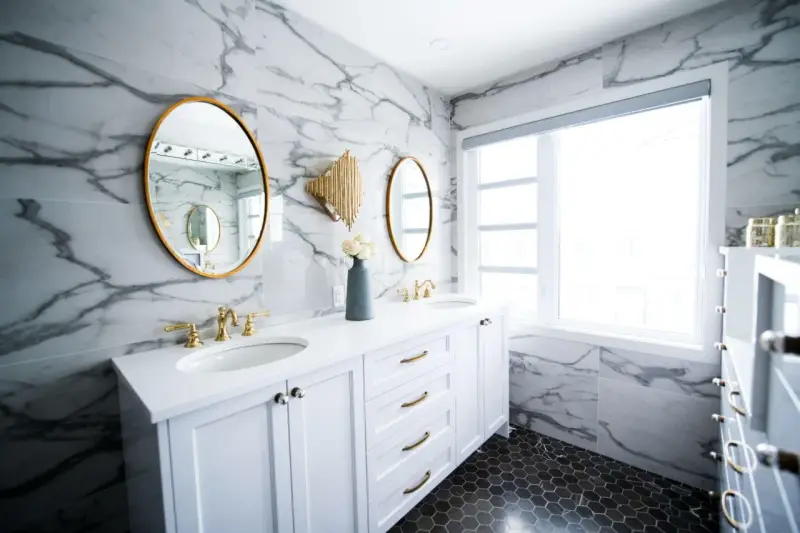 Bagno moderno con marmo, doppio lavabo e rubinetteria oro. Un'idea per capire quanto costa piastrellare un bagno di 5 mq.