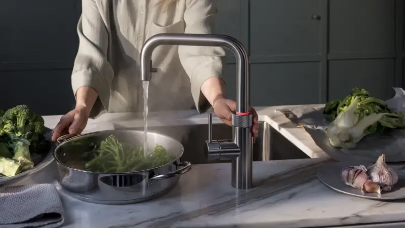 Person kocht Brokkoli mit heißem Wasser aus einem Quooker. Manche fragen sich, ob ein Quooker ungesund ist, aber hier wird er für gesunde Ernährung genutzt.