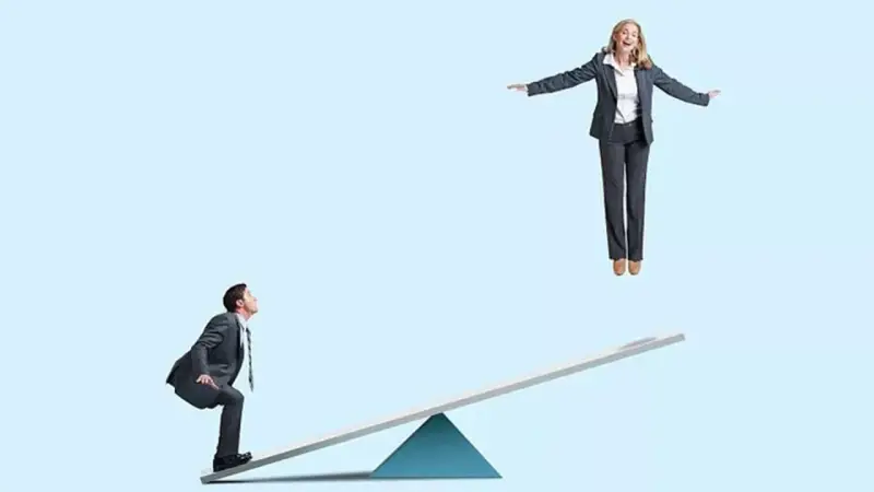Un homme en costume sur une bascule regarde une femme en l'air. Un devoir de secours pour la faire descendre ?