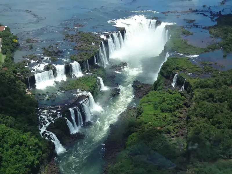 An aerial view of Iguazu Falls, a breathtaking cascade of water surrounded by lush green jungle. A perfect destination for 2 days of unforgettable adventure.