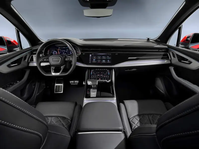 Wnętrze Audi Q7 z ekranami, kierownicą i skórzanymi fotelami.