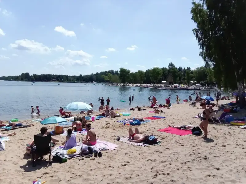Słoneczny dzień nad zalewem Sosina. Ludzie odpoczywają na plaży, kąpią się i opalają.