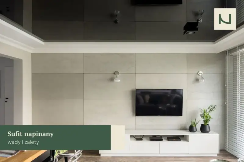 Nowoczesny salon z telewizorem na tle betonowej ściany. Lustrzany sufit napinany dodaje głębi, a subtelna **faseta** podkreśla elegancję wnętrza.