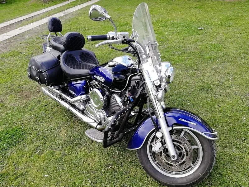 Błyszczący, niebieski motocykl Yamaha Drag Star 1100 z sakwami i dużą szybą, gotowy na podróż. Dane techniczne tego klasyka są imponujące.
