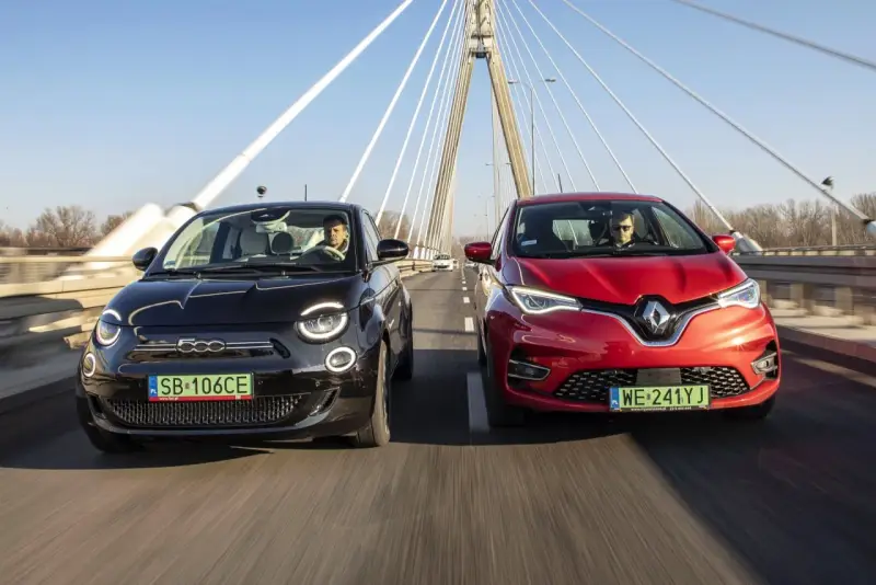 Czarny fiat elektryczny i czerwony samochód jadą po moście.