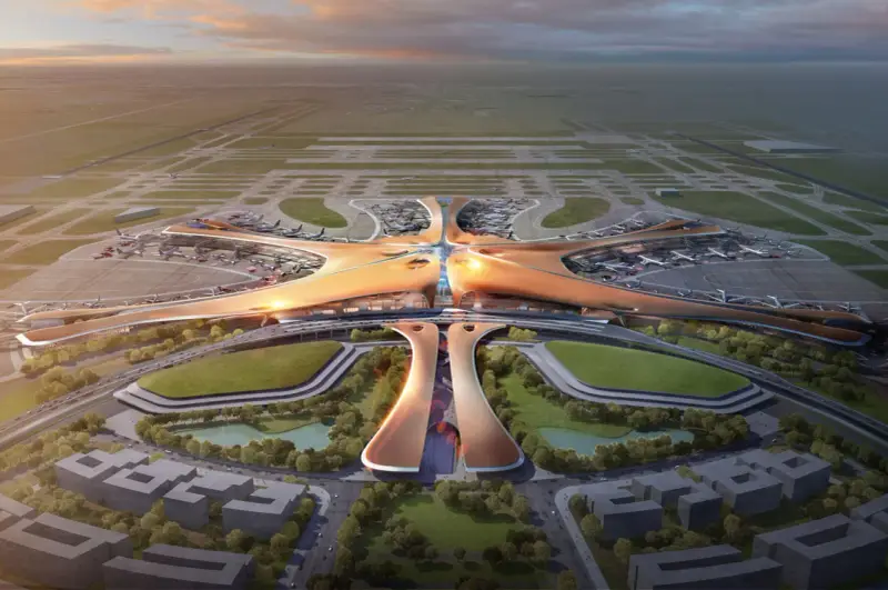 Futurystyczny terminal lotniska, przypominający rozgwiazdę, z samolotami na płycie. To największe lotnisko na świecie, z nowoczesną architekturą i otaczającą zielenią.