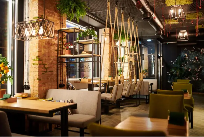 Un restaurante moderno con ladrillo visto, plantas colgantes y columpios. Un lugar acogedor que inspira lo que se necesita para abrir un restaurante.