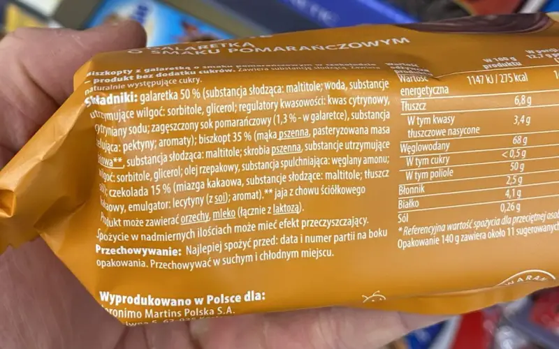 Pomarańczowe delicje kcal: biszkopt z galaretką i czekoladą. Na opakowaniu podano składniki i wartości odżywcze, w tym 275 kcal na 100g.