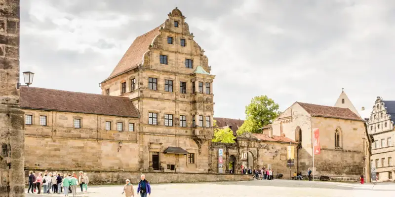 Historische Gebäude im Herzen der Bamberger Innenstadt, mit Menschen, die den Platz erkunden.