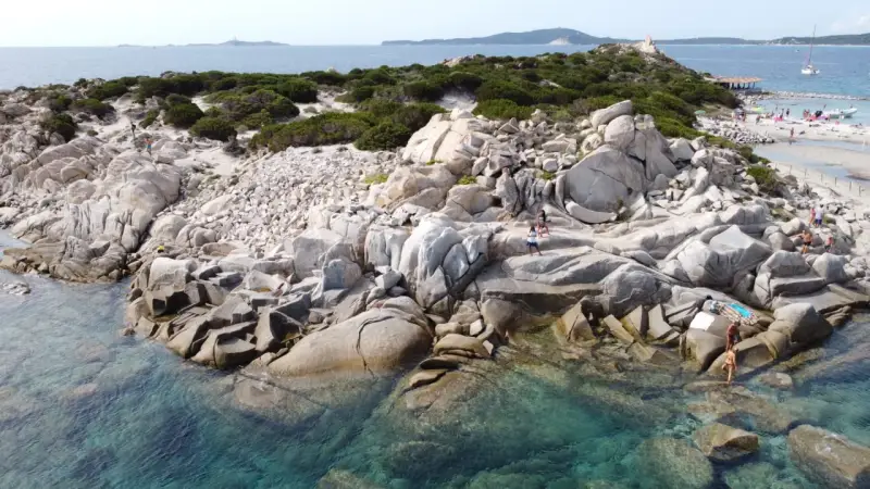 Scogliere rocciose e acque cristalline sulle spiagge a Villasimius. Turisti esplorano la costa selvaggia e si godono il sole.