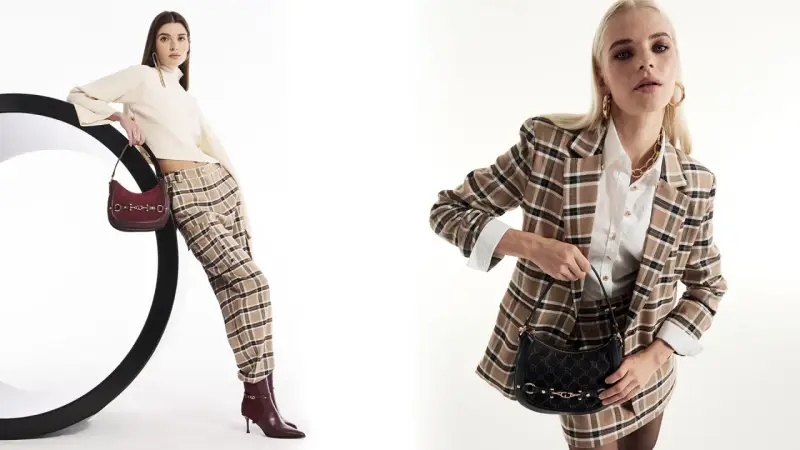 Due modelli mostrano idee outfit ufficio inverno: uno con maglione a collo alto, pantaloni a quadri e borsa bordeaux; l'altro con blazer a quadri, camicia bianca e borsa nera.