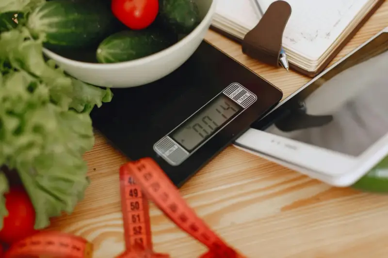 Waga kuchenna, miarka i tablet – narzędzia do planowania diety i obliczenia zapotrzebowania kalorycznego.