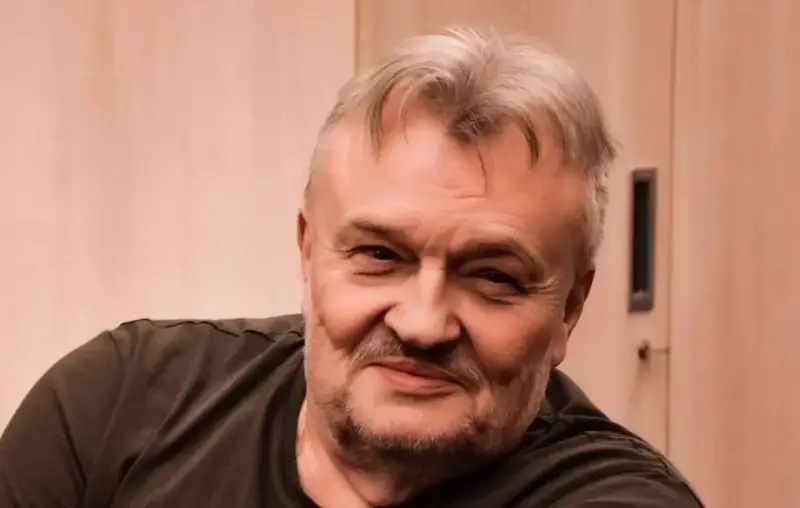 Uśmiechnięty Krzysztof Cugowski, z siwiejącymi włosami i zarostem. Zastanawiasz się, ile lat ma Krzysztof Cugowski?