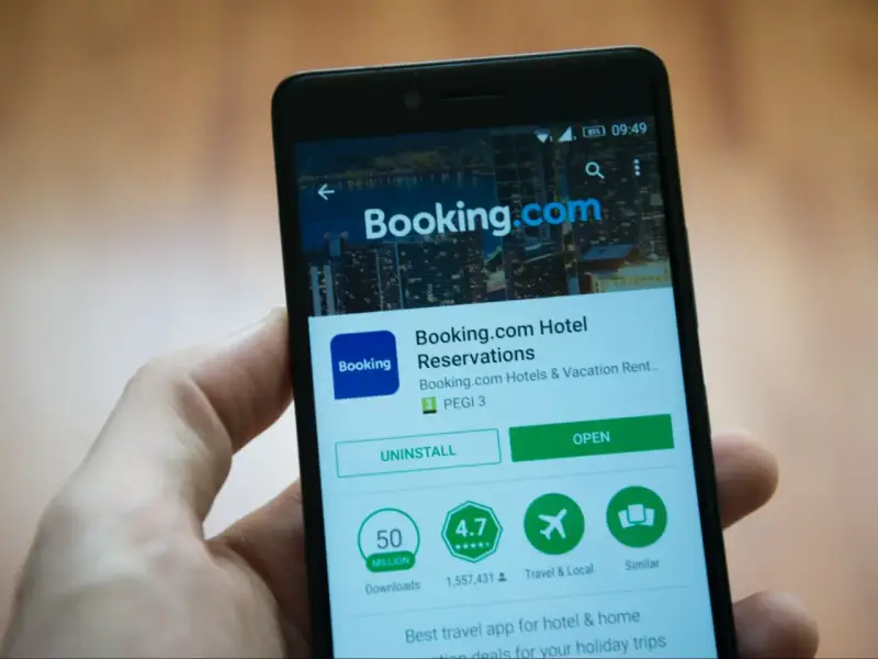 Telefon z aplikacją Booking.com. Użytkownik przegląda szczegóły, być może w celu zgłoszenia booking reklamacja.
