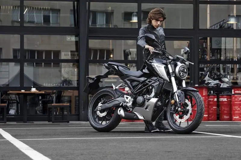 Joven con chaqueta de cuero junto a una moto negra, listo para obtener su a1 permiso de conducir.