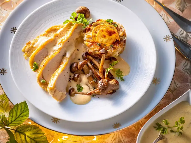 Délicieux poulet de Bresse à la crème, servi avec des champignons et une garniture dorée. Une recette qui éveille les papilles.