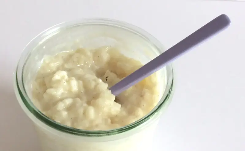 Budino cremoso, profumato alla vaniglia, come quello della ricetta della nonna, pronto per essere gustato con un cucchiaino viola.