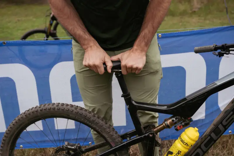 A rider adjusts their seat on a full-suspension bike, ready for an enduro mountain biking adventure.