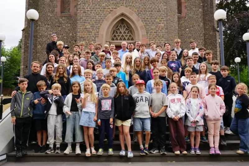 Große Gruppe von Kindern und Jugendlichen vor einer Kirche, die an einem christlichen Ferienlager teilnehmen.