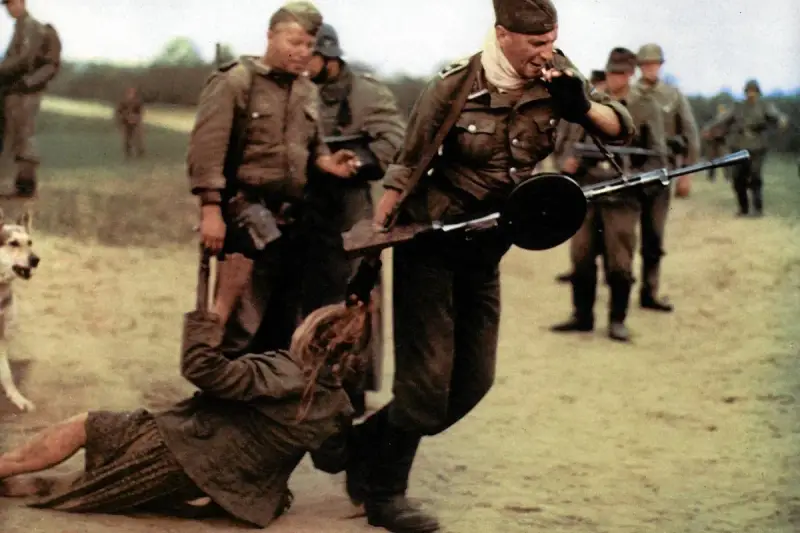 Żołnierz z karabinem ciągnie kobietę za włosy. Obok stoi pies. Idź i patrz, co się dzieje.