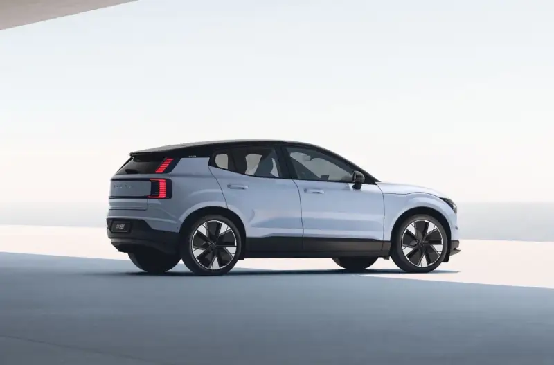 Jasnoszary Volvo EX30 z czarnym dachem i futurystycznymi felgami. Ten elektryczny SUV oferuje imponujący zasięg, idealny na długie podróże.