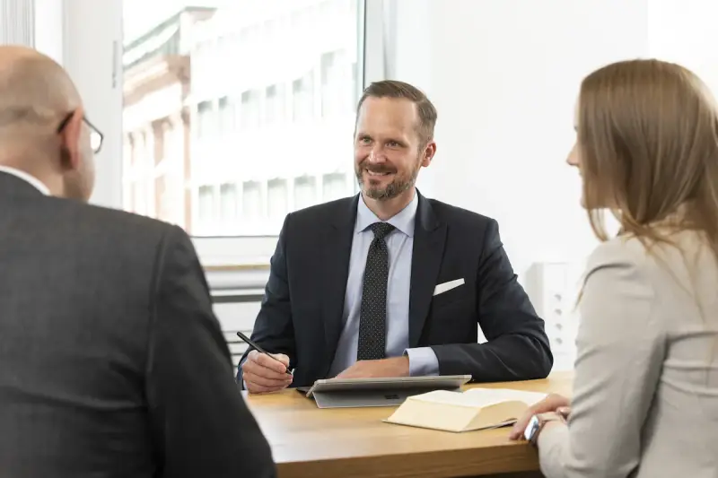 Anwalt für Versicherungsrecht bietet kostenlose Erstberatung. Drei Personen im Gespräch am Tisch.