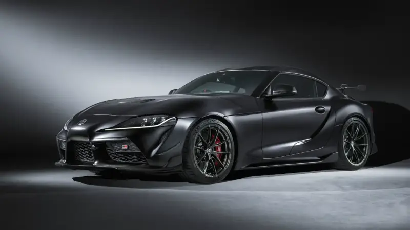 Matowa czerń podkreśla agresywną sylwetkę sportowego coupe Toyota GR Supra. Widoczne czerwone zaciski hamulcowe i aerodynamiczne dodatki.