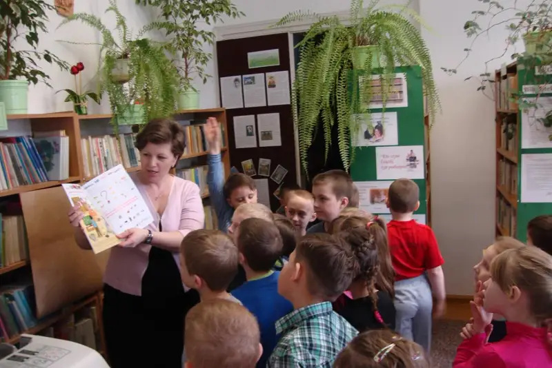 Nauczycielka czyta dzieciom książkę, tworząc inspirujące lekcje biblioteczne scenariusze. Dzieci słuchają z uwagą.