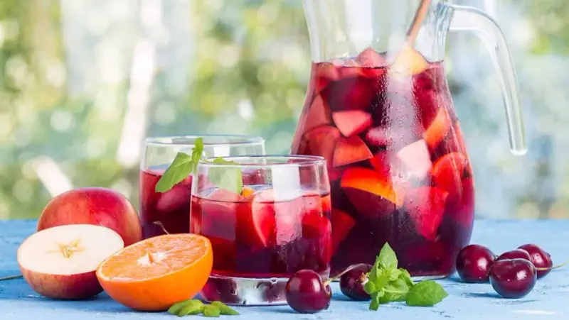 Une carafe et des verres de sangria rouge remplis de fruits frais, parfaits pour une recette de sangria rouge estivale.
